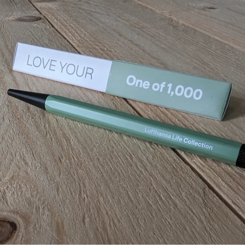 Der Drehgriffel individuell gestaltbar. Green pen with print “Lufthansa Life Collection” and box with “LOVE YOUR” and “One of 1,000”. FR: